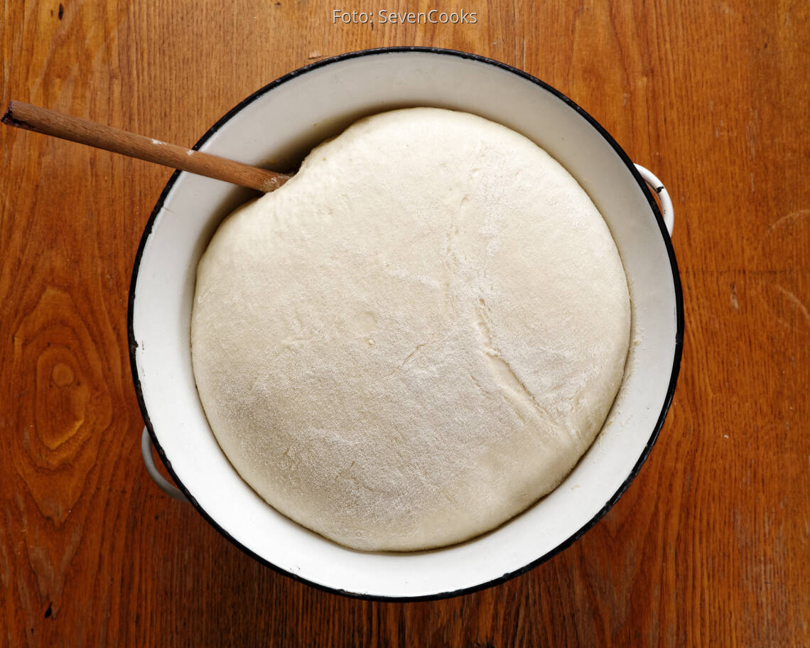 Hefeteig in Emailleschüssel auf Holztisch