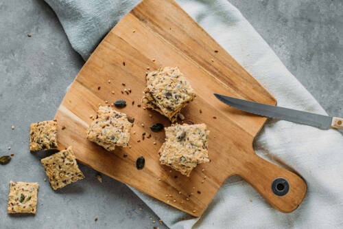 Selbst gemachtes Knäckebrot in quadraten gestapelt von oben auf einem Holzbrett