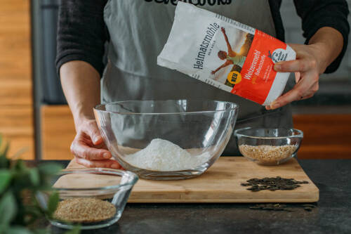 Eine Schüssel mit Mehl und eine Packung von "Weizenmehl plus Ballaststoffe" von Heimatsmühle