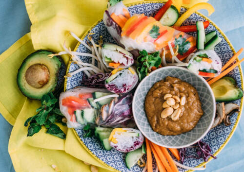 Bunter Teller mit unterschiedlich gefüllten Summerrolls, dazu ein Erdnuss-Dip, von oben fotografiert.