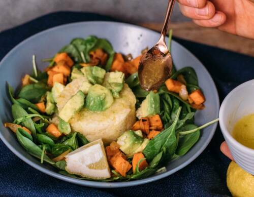 Hirse-Bowl mit Dressing in Teller vor dunklem Hintergrund.