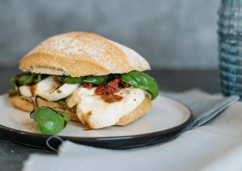 Italienisches Sandwich mit Tomaten, Mozarella und Basilikumblättern. Von vorne fotografiert.