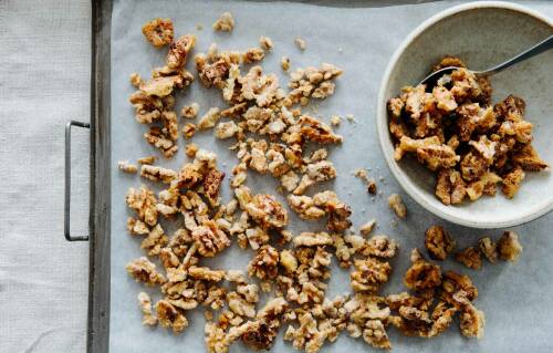 Im Ofen karamellisierte Walnüsse auf Backpapier und in einer Schüssel.