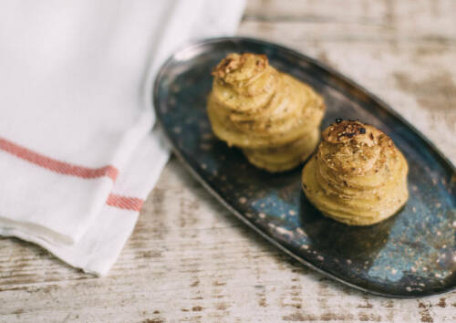 Kleine Gratintürmchen von der Kartoffeln auf einer Platte, von oben fotografiert.