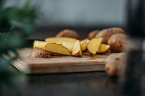 Aufgeschnittene Kartoffeln auf einem Holzbrett.