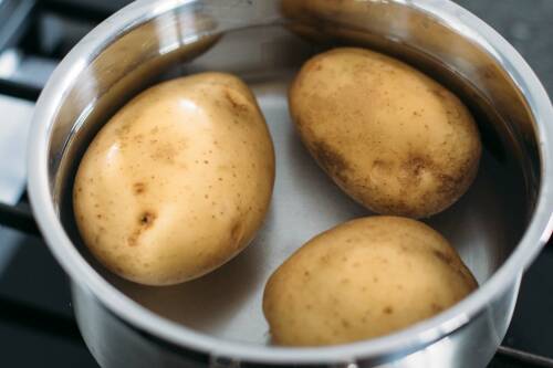 Kartoffeln in einem Topf mit kaltem Wasser, von oben fotografiert.