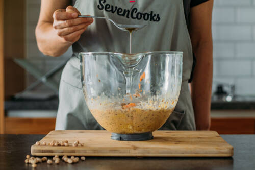 Teig mit Öl in Rührschüssel und Händen vor hellem Hintergrund.