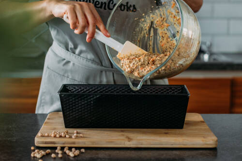 Kichererbsenbrot in Kastenform mit Händen und Schüssel vor dunklem Hintergrund,