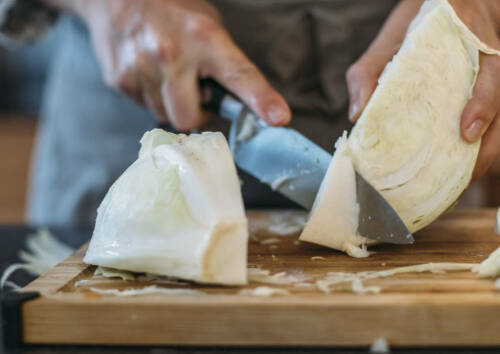 Mit einem scharfen Messer wird der Strunk aus einem geviertelten Weißkohl entfernt.