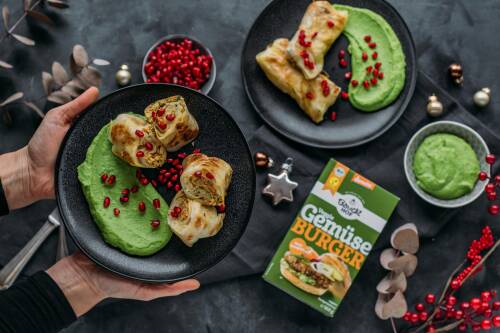 Selbstgemachte Kohlrouladen mit Gemüseburger-Füllung auf schwarzem Teller, daneben Packung für Gemüseburger von Bauckhof