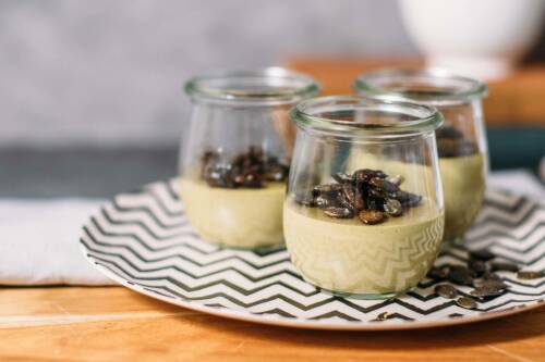 Kürbiskern Panacotta in Gläsern auf Teller vor hellem Hintergrund.