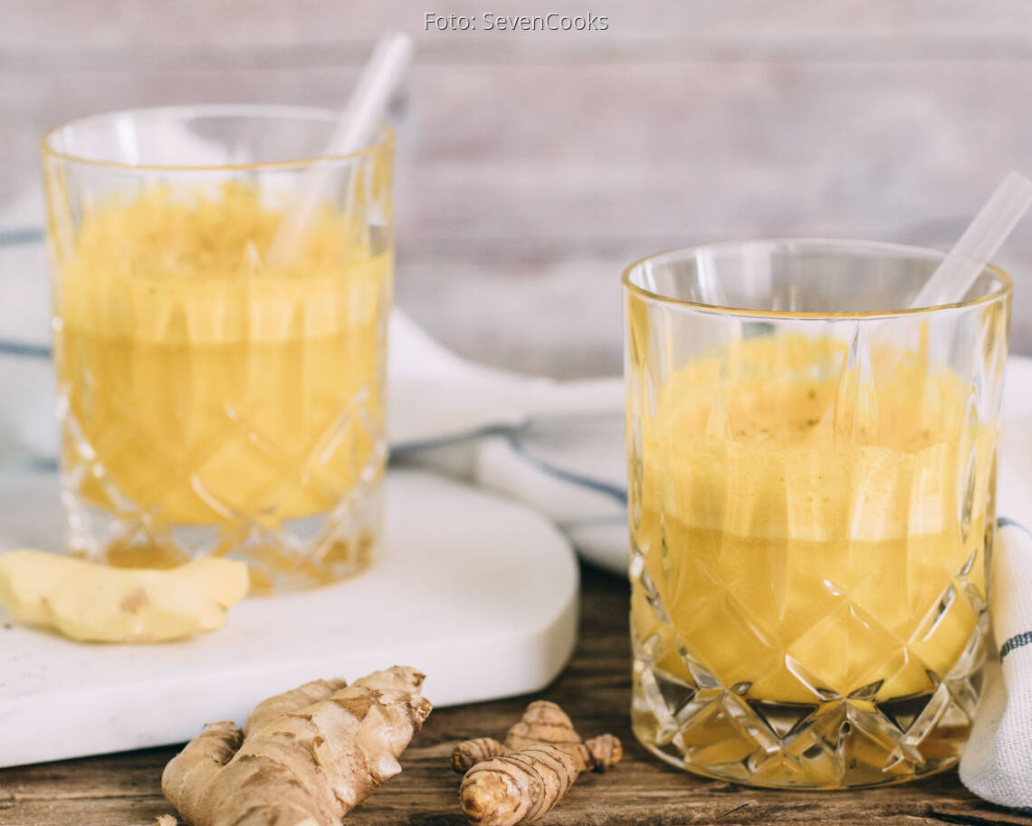 Gelber Kurkuma-Ingwer Immunbooster in zwei Gläsern mit Strohhalm.
