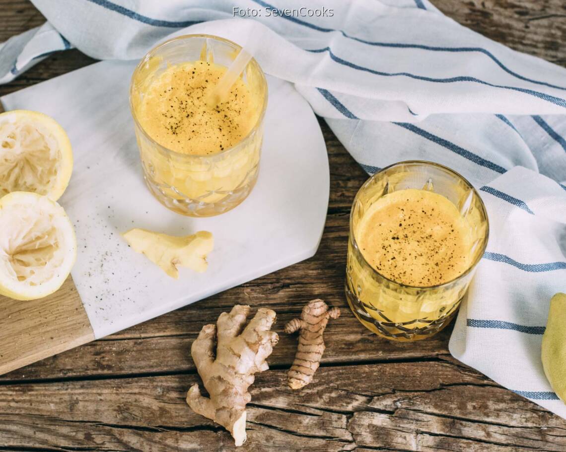 Draufsicht auf gelben Kurkuma-Ingwer Immunbooster in zwei Gläsern mit Strohhalm.