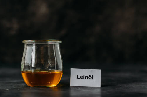 Leinöl in Glas vor dunklem Hintergrund.