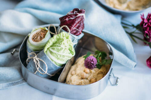 Lunchbox mit veganen Wraps vor hellem Hintergrund.