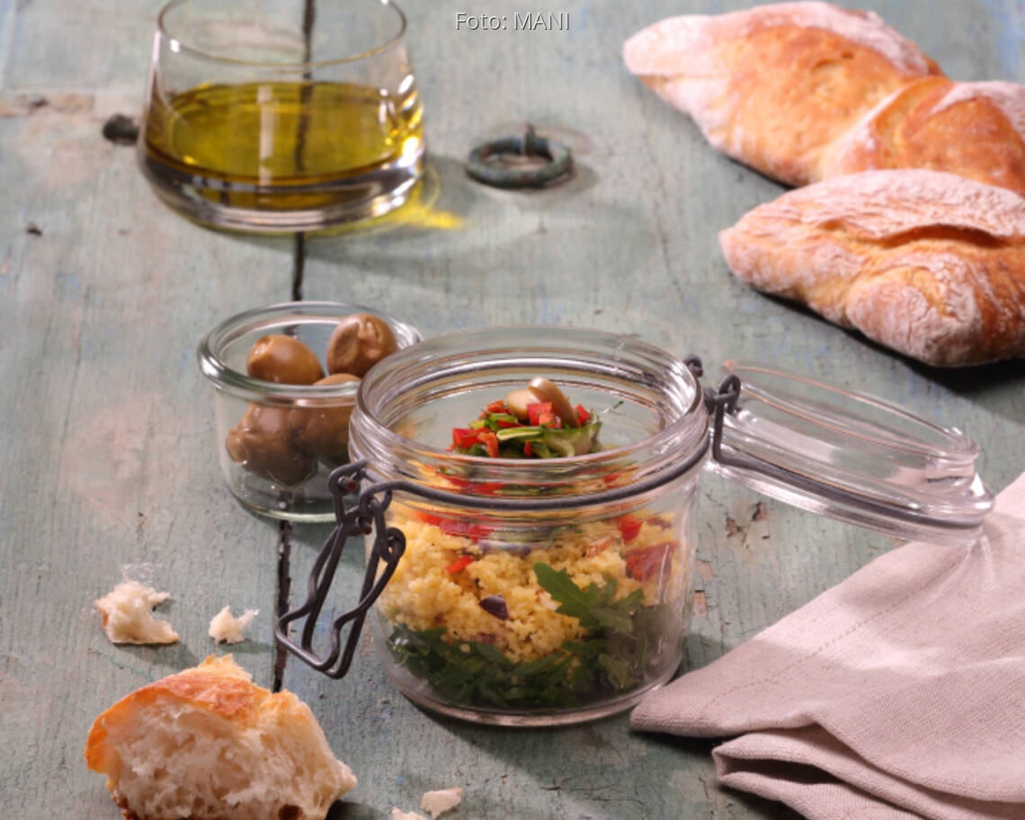 Glas mit Maistaboulet mit Olivenöl, Fladenbrot auf Holztisch