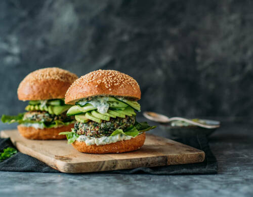 Mangold-Burger auf Schneidebrett vor dunklem Hintergrund.