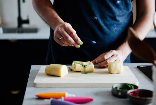 Eine Hand streut grünes Lebensmittelpulver auf Marzipan.