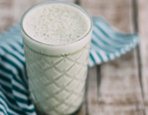 Matcha Latte in Glas vor hellem Hintergrund.