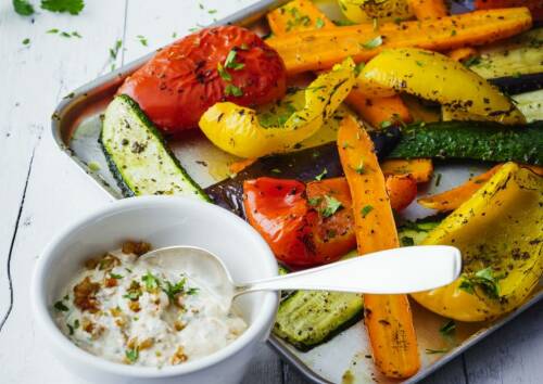 Buntes Grillgemüse mit Quark als Eiweißlieferant auf einem Blech von vorne fotografiert.