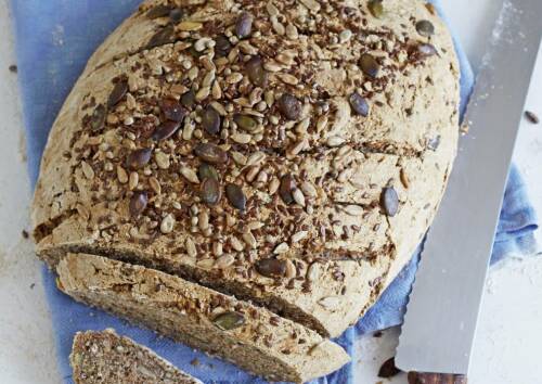 Laib Mehrkornbrot, angeschnitten, daneben ein Messer.