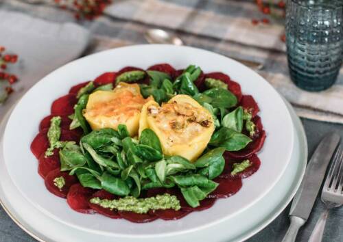 Mini-Gemüseaufläufe auf Feldsalatbett, Rote Bete Carpaccio daneben Pestoklekse. Herrlich bunt in Grün und Rot. Von oben fotografiert.