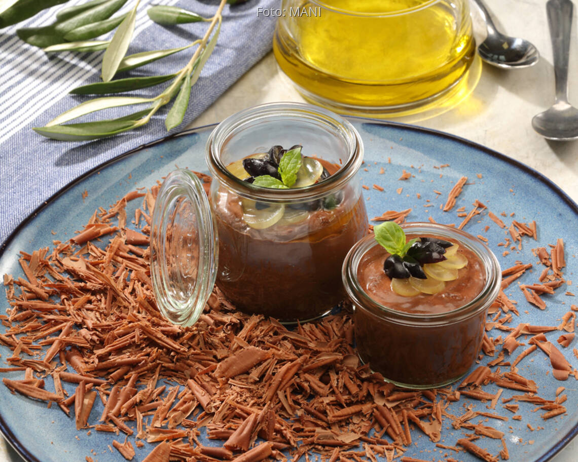Schokomousse in Gläschen auf blauem Teller mit Olivenöl und Tuch dekoriert