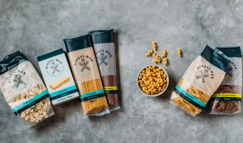 Verschiedene Nudelvarianten von DINKEL MAX auf grauem Hintergrund.