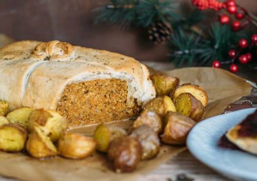 Nussbraten im Blätterteig mit Rosmarinkartoffeln. Von der Seite fotografiert.