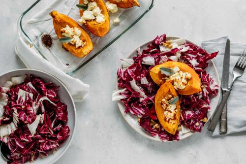 Ofenkürbis mit nussigem Herbstsalat und Radicchio auf Tellern und Schüsseln vor weißem Hintergrund.