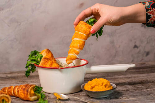 Oster Karotten aus Hefeteig mit Hand und weißer Schüssel vor hellem Hintergrund.