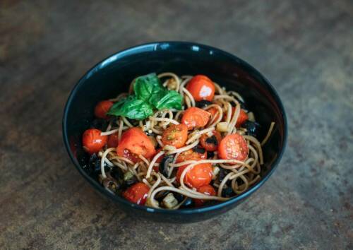 Mediterran: Pasta mit Kirschtomaten, Aubergine und Basilikum in einer schwarzen Schüssel. Von oben fotografiert.