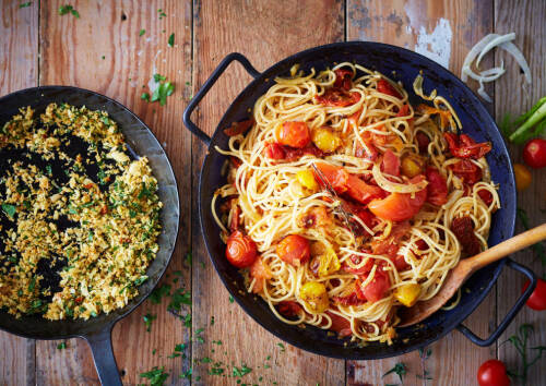 Leckere Spaghetti mit Ofentomaten in einer Pfanne, von oben fotografiert.