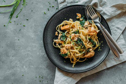 Schwarzer Teller von oben mit Pasta mit Spinat-Lachs-Sauce