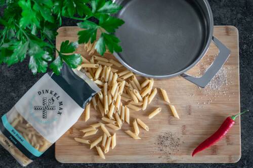 Penne neben einem Topf mit Wasser