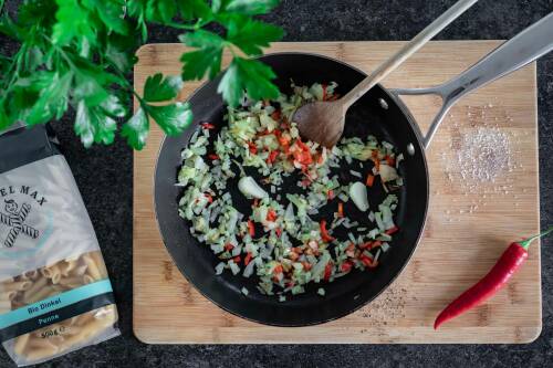 Zwiebeln, Knoblauch und Chilischoten in einer Pfanne.