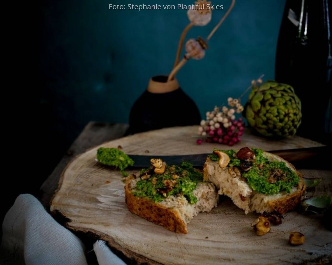 Grünkohl-Pesto auf Baguette liegt auf einer Holzscheibe mit Deko
