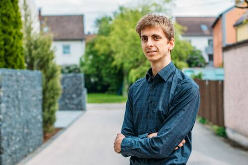 Webentwickler Philipp in einem blauen Hemd vor einem Baum.
