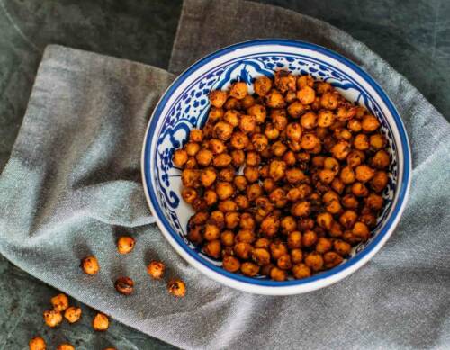 Pizza-Kichererbsen in blauer Schale vor dunklem Hintergrund.