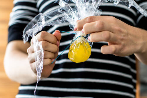 Verschließe die Frischhaltefolie mit dem Ei darin mit einem Haushaltsgummi luftdicht.