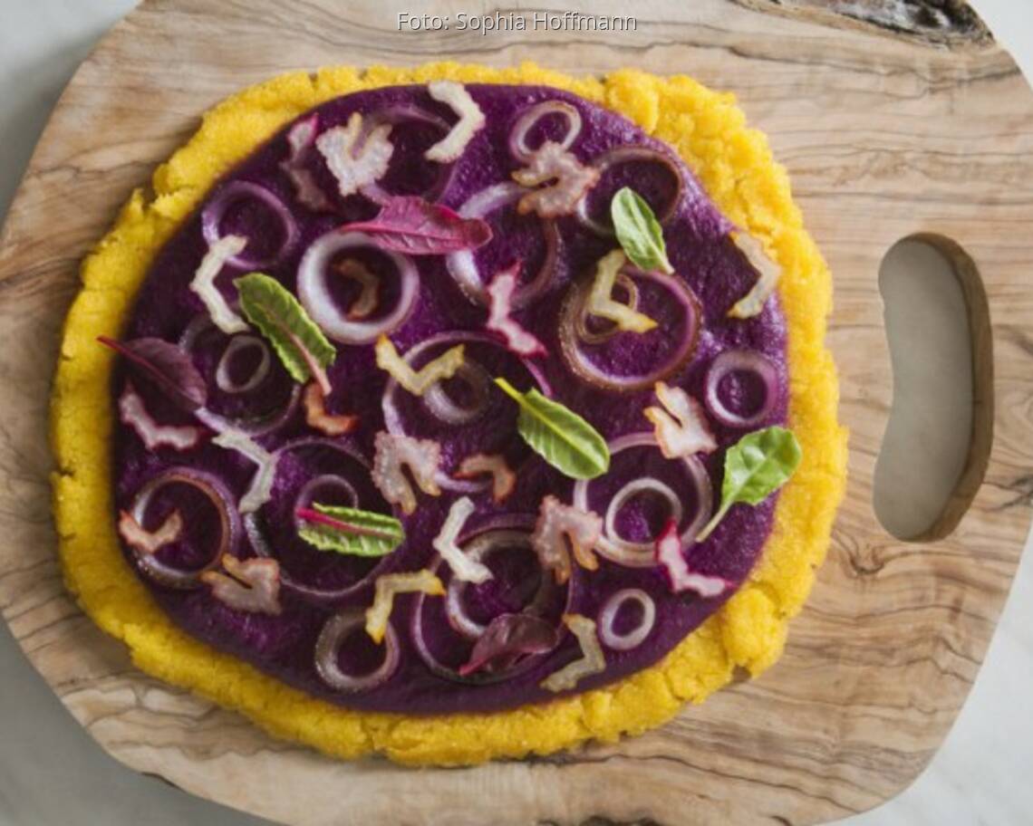 Holzbrett mit Flammkuchen aus Polenta, Blaukraut-Pesto und Mangold