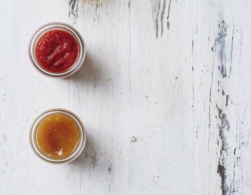 Quittengelee in rot und gelb in zwei kleinen Gläsern von oben fotografiert vor weißem Hintergrund.