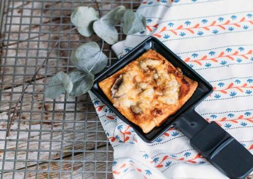 Mini-Pizza mit Pilzen, Tomatensauce und Käse im Pfännchen. Von oben fotografiert.