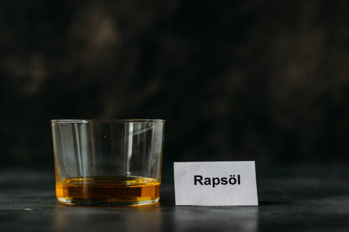 Rapsöl in Glas vor dunklem Hintergrund.