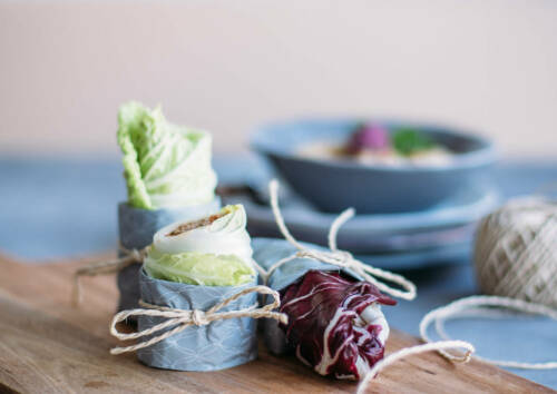 Kleine leckere Rohkostwraps mit Kohl und anderem Gemüse gefüllt. Von vorne fotografiert.