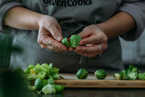 Ein Frau entfernt die äußeren Blätter von Rosenkohl.
