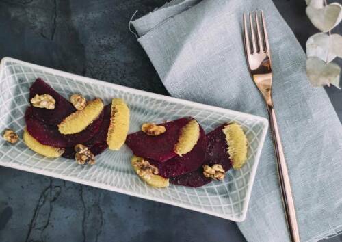 Carpaccio mit roten Beten auf einer grauen Platte vor dunklem Hintergrund. Von oben fotografiert.