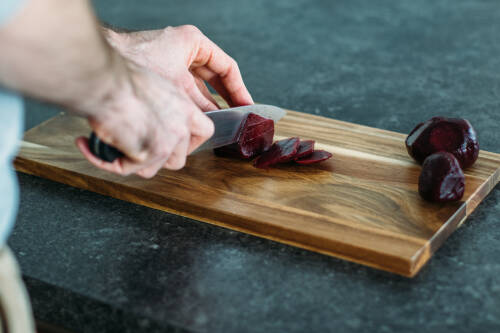 Rote Bete werden auf einem Holzbrett geschnitten