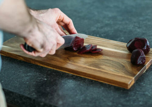 Rote Bete werden auf einem Holzbrett geschnitten.