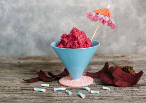 Selbst gemachter Rote-Bete-Hummus, schön angerichtet in einer blauen Schale mit Schirmchen.